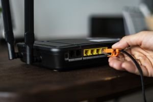 man-plugging-ethernet-cable-wireless-router